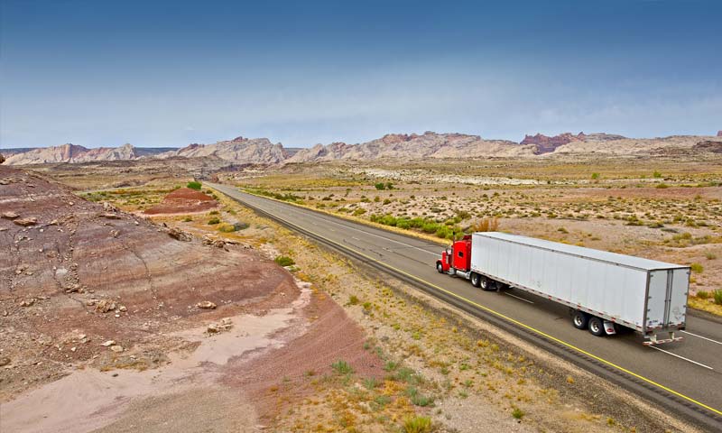 white and red semi truck driving down rural highway