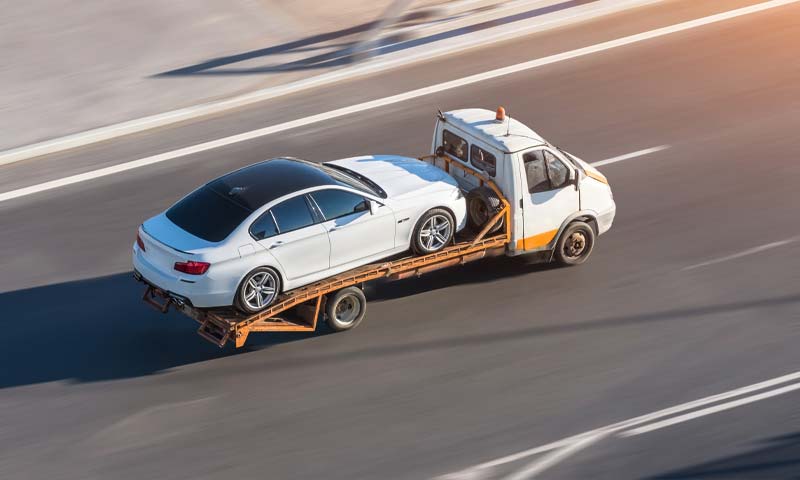 flat bed semi truck hauling car along highway